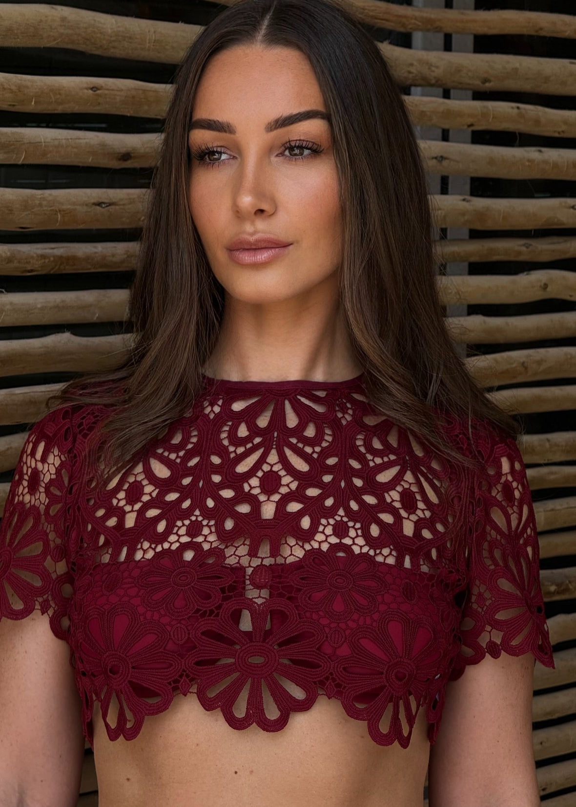 Woman wearing a red lace top against a wooden background